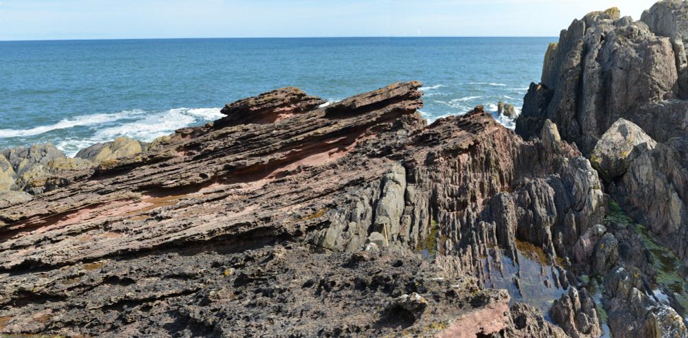 The major angular unconformity at Siccar Point on the east coast of Scotland.  Here the more gently sloping Devonian sandstones (c.375 Ma) overlay the near vertical Silurian greywackes (c.440 Ma).  Viewed by James Hutton while on a boat trip in 1788, this was one of the sites that solidified Hutton and Lyell's new concepts of Earth's geology: that it was formed by slow continuous processes similar to those still occurring today operating over vast periods of time.