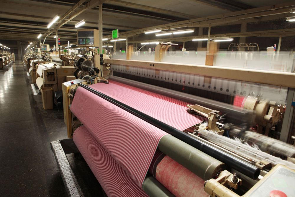 Wide sheets of fabric running through a large machine with several rollers