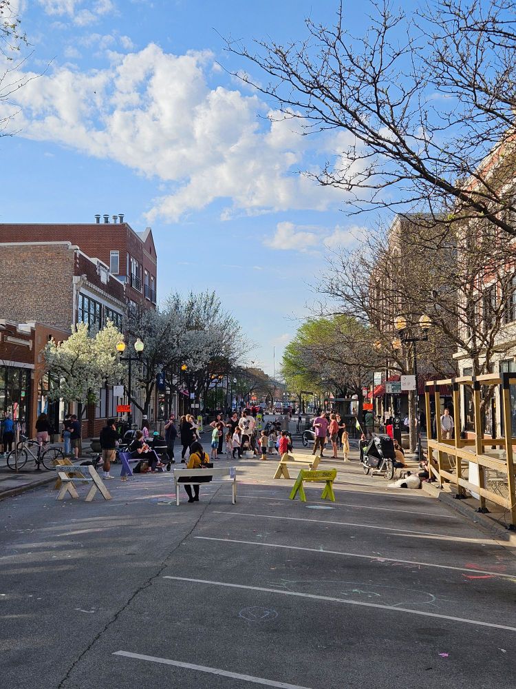 Photo of benches in the middle of a street with lots of people 
