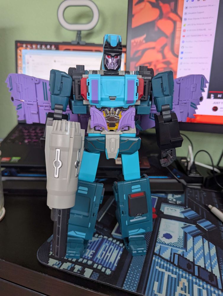 transforming robot action figure. Humanoid holding large gun. Has wings on back.