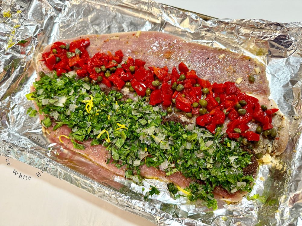 A pork loin that has been cut in half, flattened, and covered with the parsley-kalamata mix on one side, and roasted red bells with capers on the other. This is then rolled up, wrapped in prosciutto, and baked.