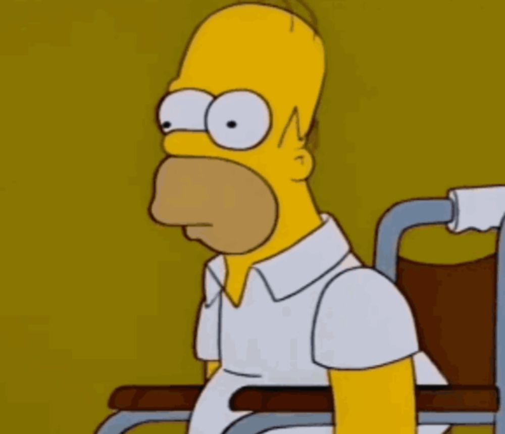 homer simpson is sitting in a wheelchair and looking at the camera