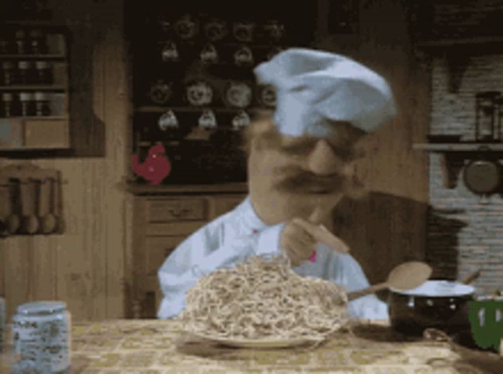 a man in a chef 's hat is eating noodles with a fork