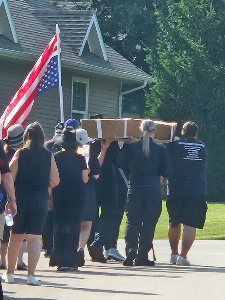 Carrying a cardboard coffin in the funeral procession.
