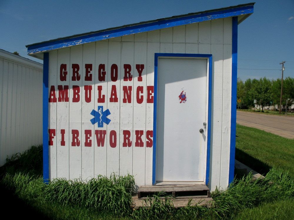 A small firework shack outside a tiny volunteer fire department in South Dakota labeled "Gregory Ambulance and Fireworks"