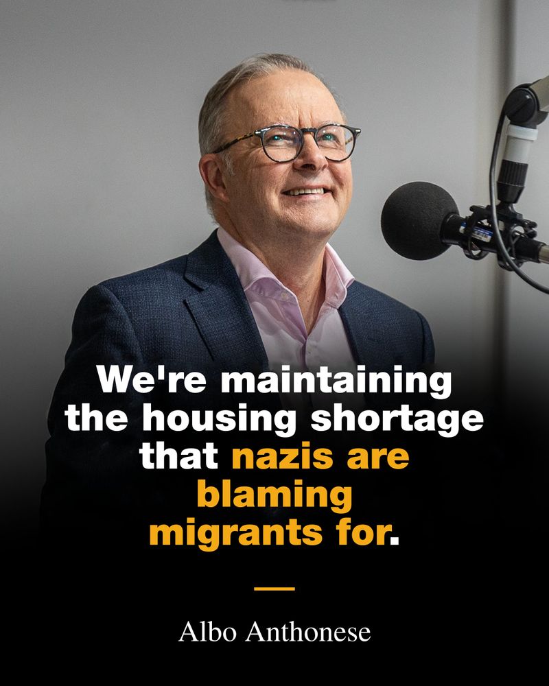 Smug git Anthony Albanese grinning into the studio lights with a microphone pointing at his face. 