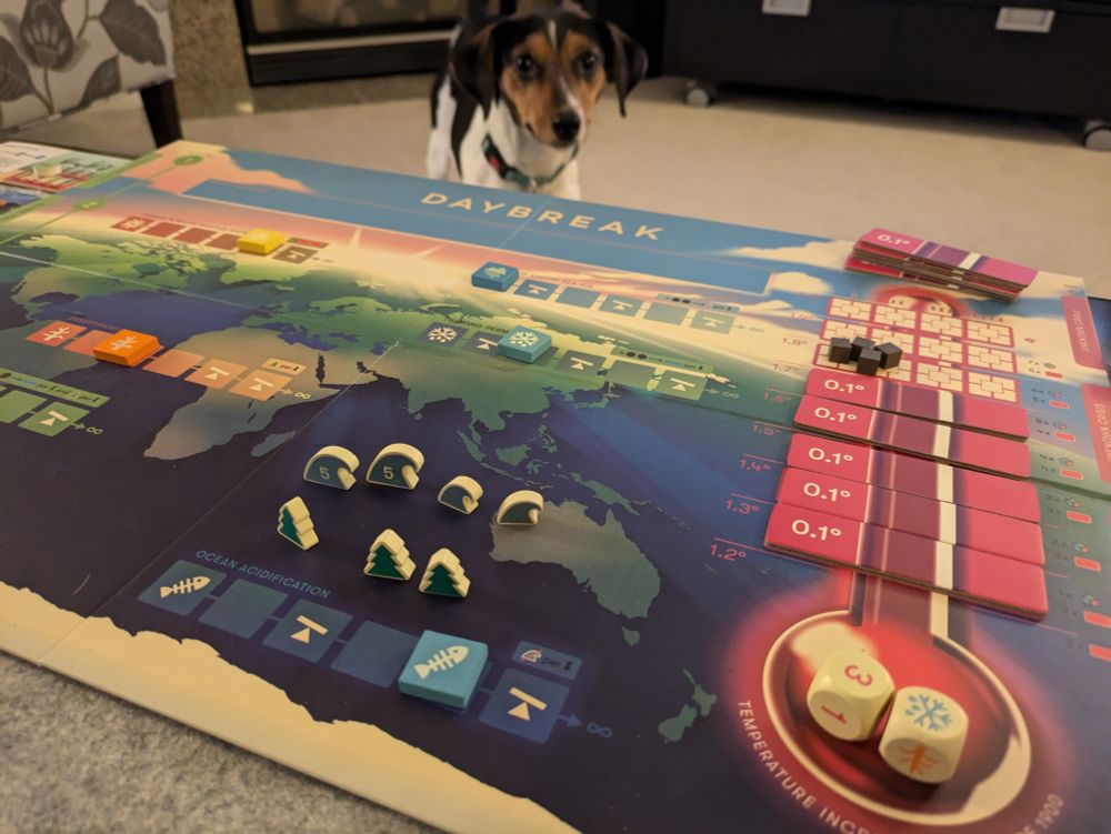 The board game Daybreak, with Sticky Rice the beagle mix in the background