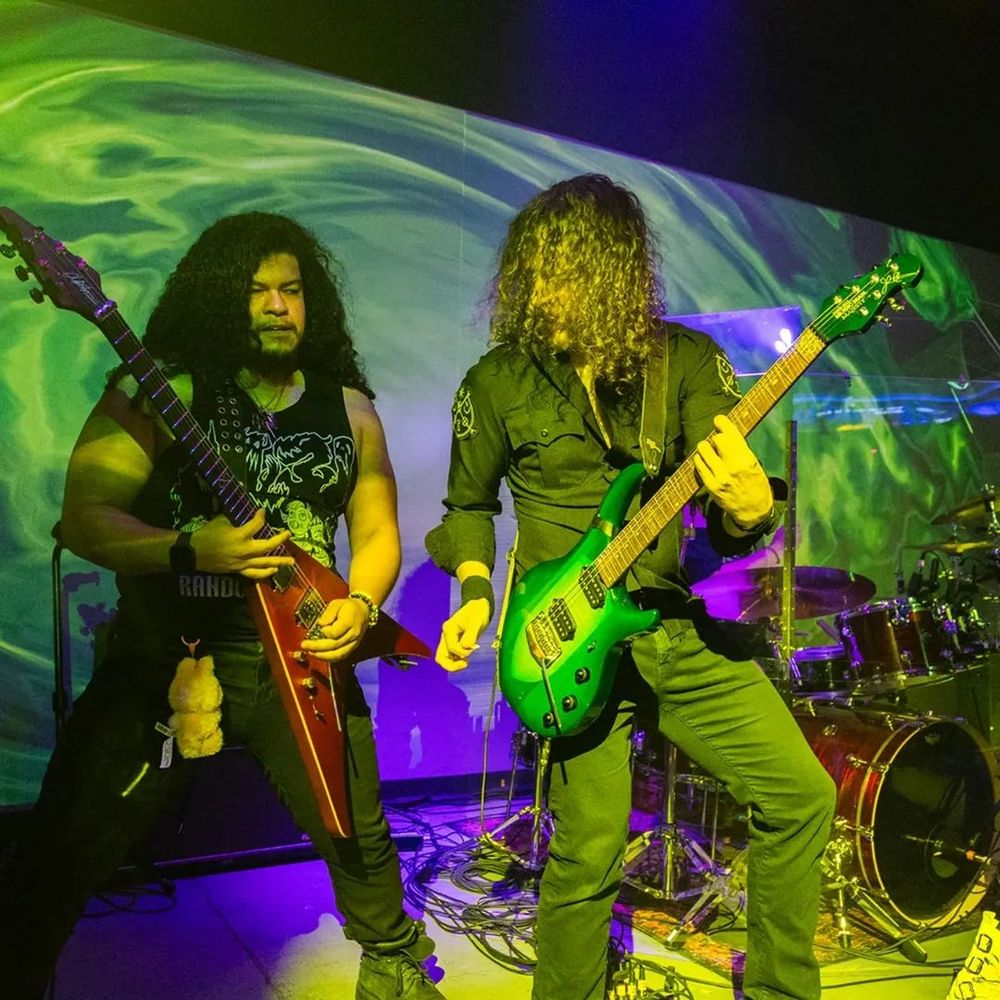 Two men with long hair playing electric guitars 