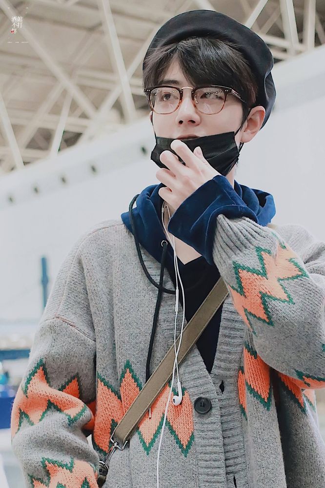 XZ in a grey sweater with orange zig zag stripe around the middle