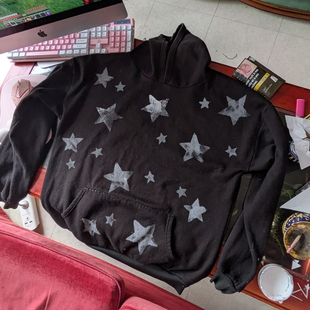 hoodie noir avec des étoiles blanches peintes dessus