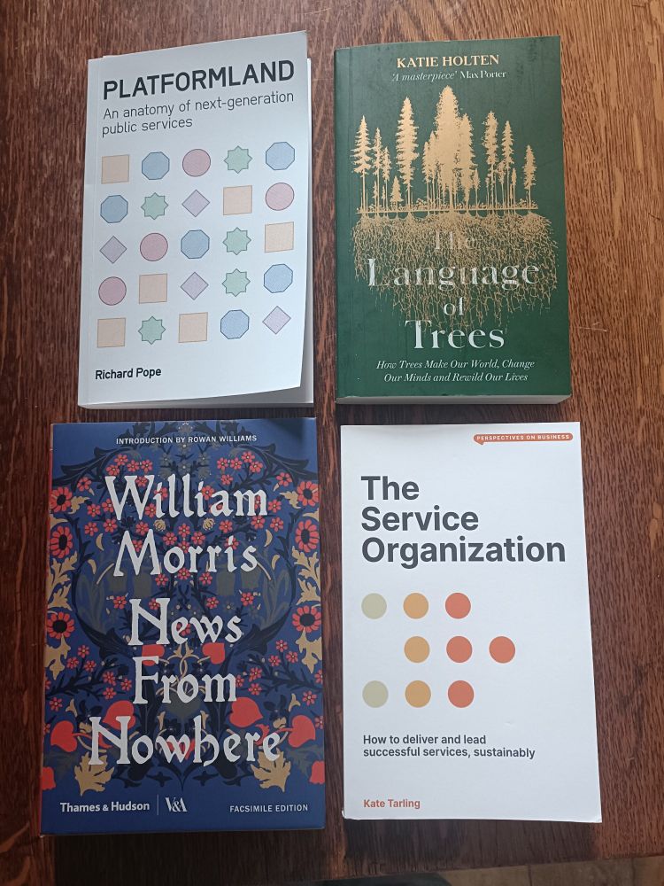 4 books laid cover up on a wooden table - Platformland by Richard Pope, The Language of Trees by Katie Holten, News from Nowhere by William Morris and The Service Organization by Kate Tarling
