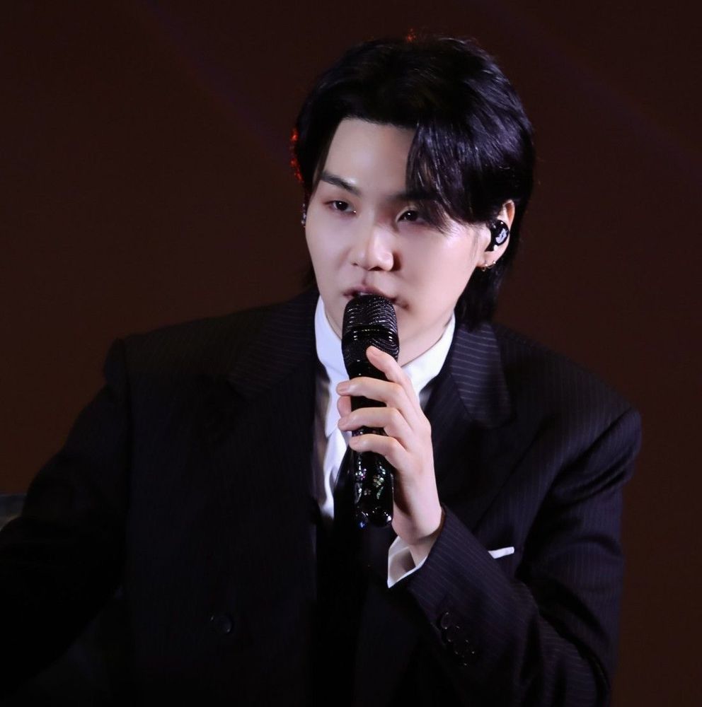 Yoongi in a suit with a microphone in hand
