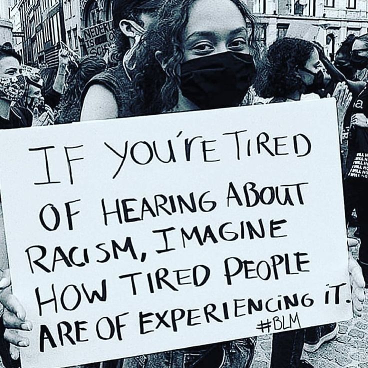 Eine Frau hält ein Schild, auf dem steht 
"IF YOU'RE TIRED OF HEARING ABOUT RACISM, IMAGINE HOW TIRED PEOPLE ARE OF EXPERIENCING IT. #BLM