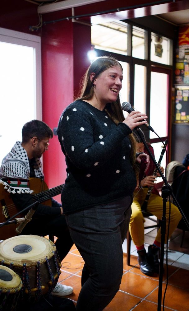 Nerea dando la bienvenida y presentando la exposición, detrás los músicos del grupo Mar Blanco se preparan para su pequeño concierto.
