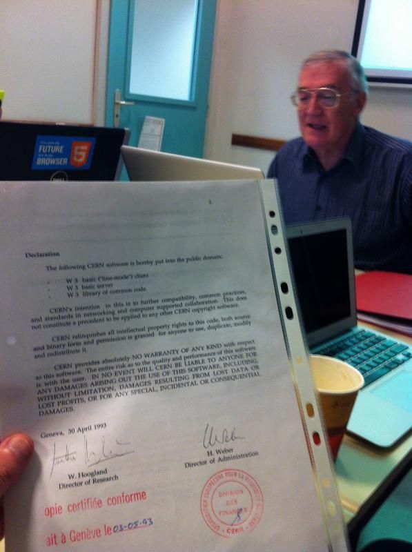 A copy of the document that put the World Wide Web into the public domain, being held by me at CERN while Robert Calliau talks in the background.