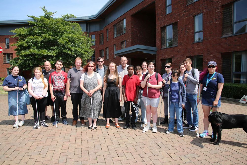 A group of people standing in a courtyard on the University of Worcester campus smiling in the sunshine
