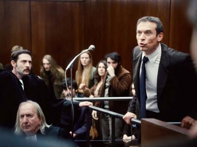 Image de la scène du film "Le procès Goldman" où Goldman traite la police de racistes