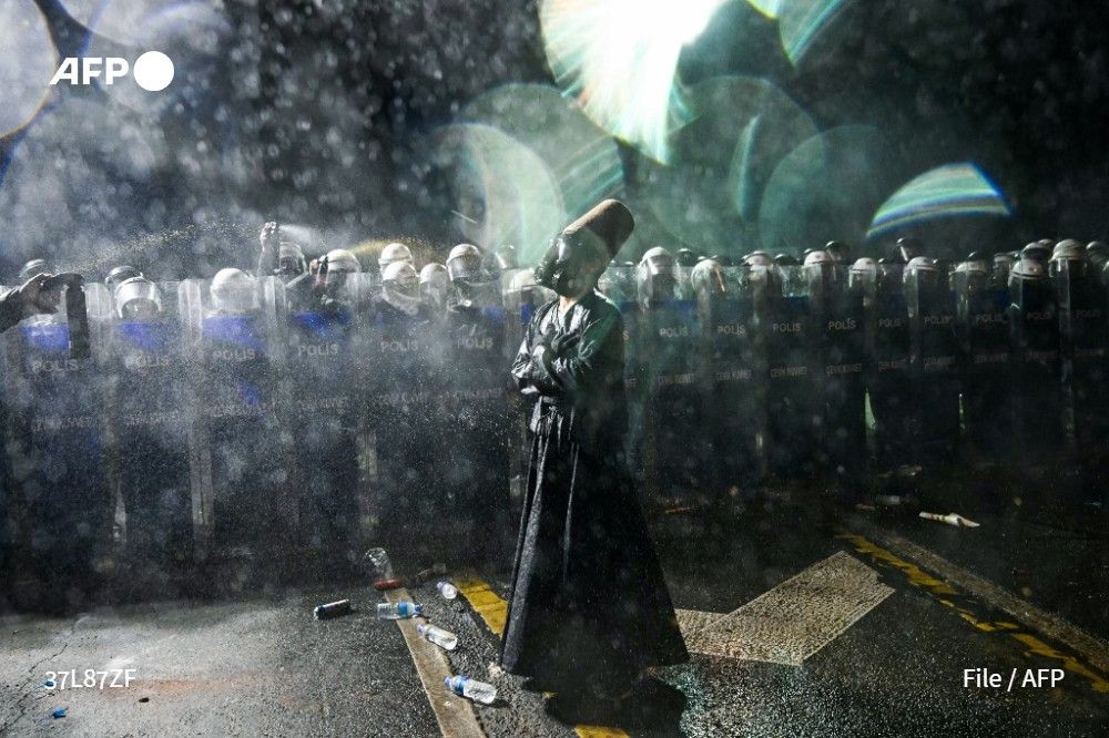 A whirling dervish stands in front of Turkish riot police using pepper spray to disperse protesters during a rally in support of Istanbul's arrested mayor in Istanbul Municipality, on March 23, 2025