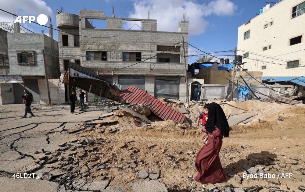 A Palestinian woman walks over a destroyed road in the aftermath of an Israeli strike in Khan Yunis, southern Gaza Strip, on May 14, 2025. 