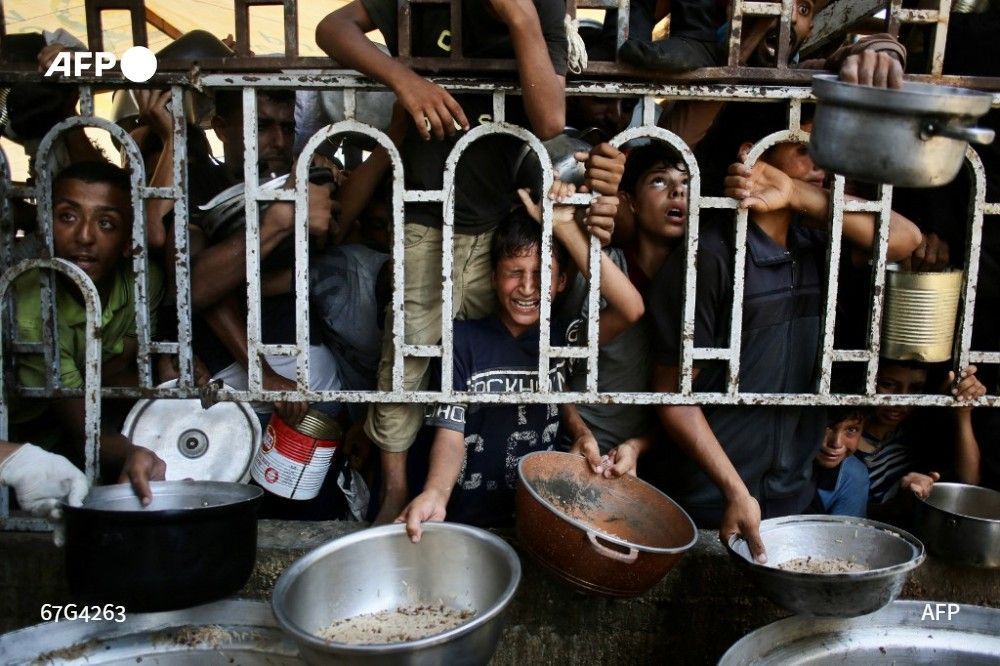 Palestinian children wait for a meal at a charity kitchen in the southern Gaza Strip, on July 22, 2025.