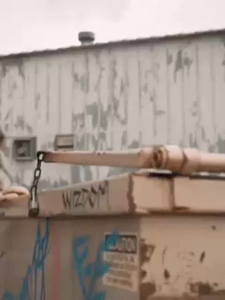 a dumpster with graffiti on it is sitting in front of a building with a chain attached to it .