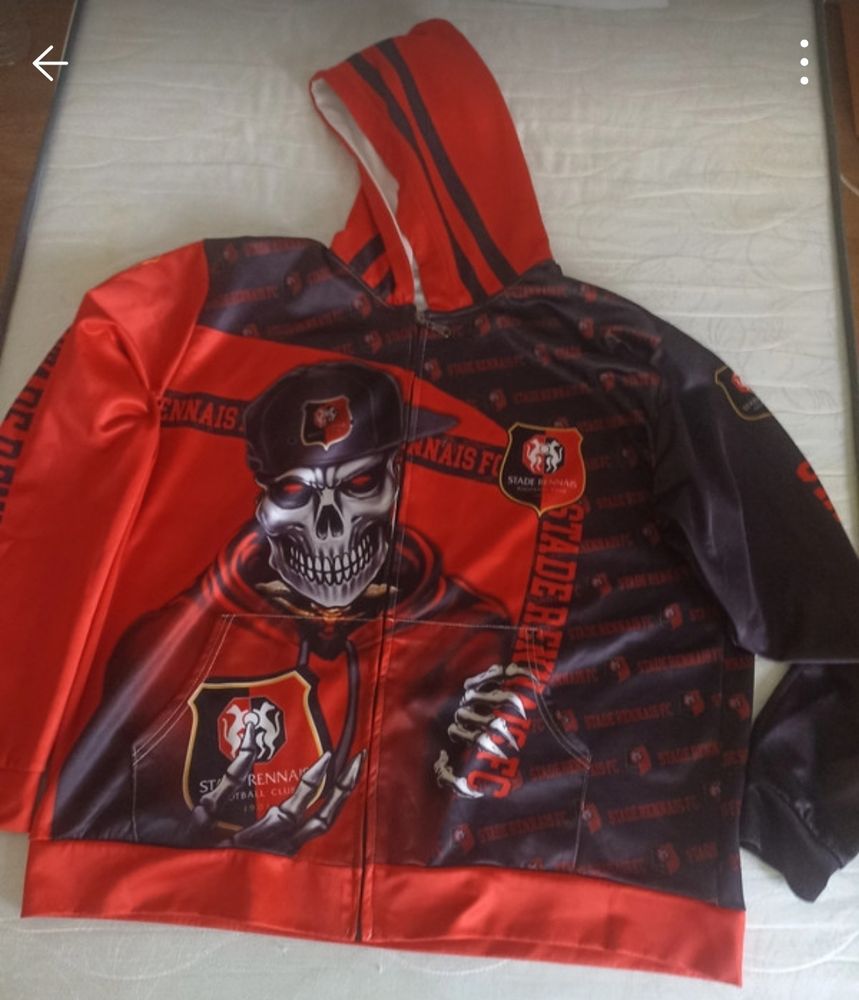 Photo d'une veste Stade Rennais de face, un squelette tient le logo du club dans une main et porte une casquette SRFC