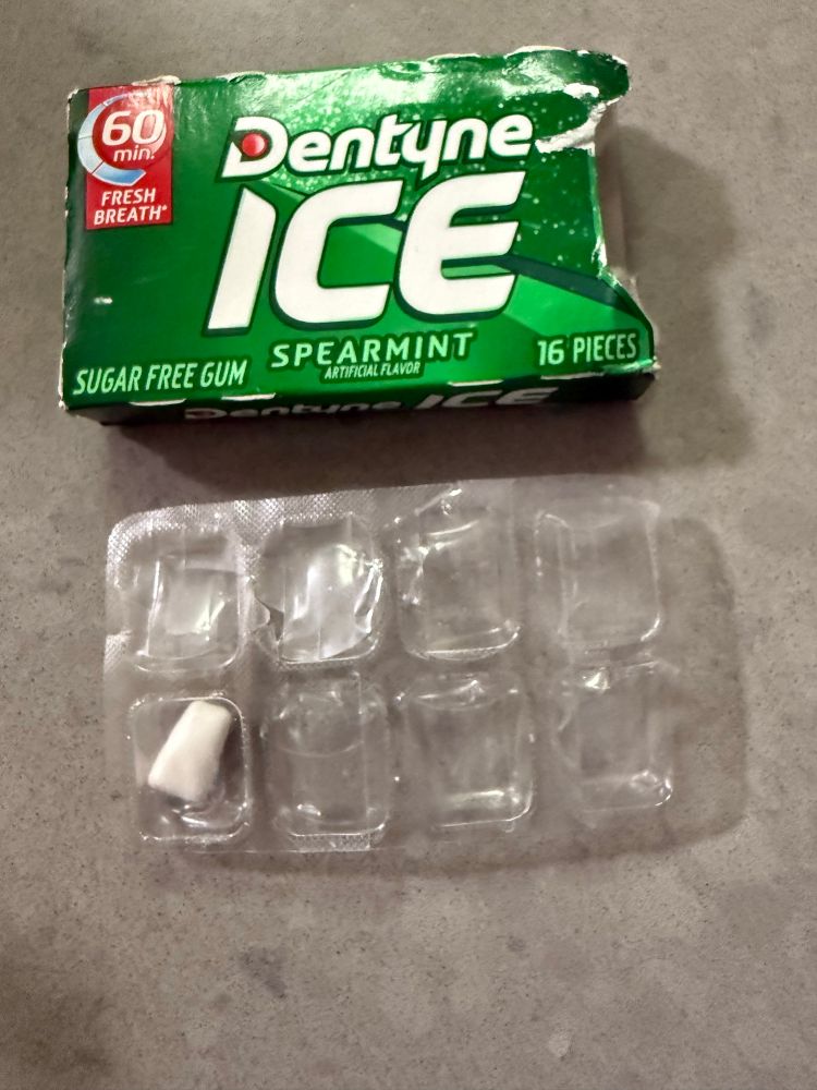 A pack of Dentyne chewing gum, with an undersized, oddly shaped piece in the package.