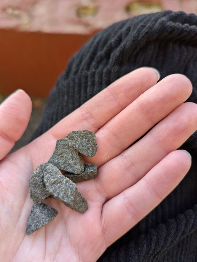 A hand holding a small pile of grey gravel stones