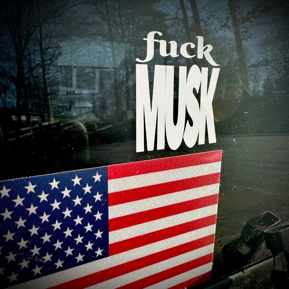 An auto window sticker that reads "Fuck Musk" above an American Flag.