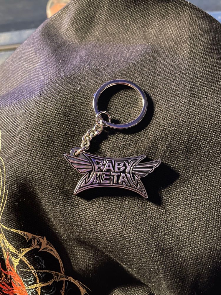 A photo of a metal charm shaped like the babymetal logo. 