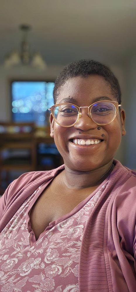 Black woman with short hair and clear rimmed glasses