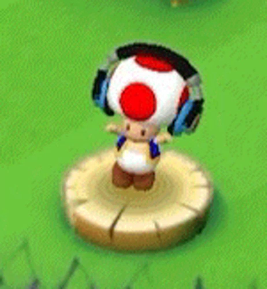 a toad wearing headphones is standing on a stump in the grass .