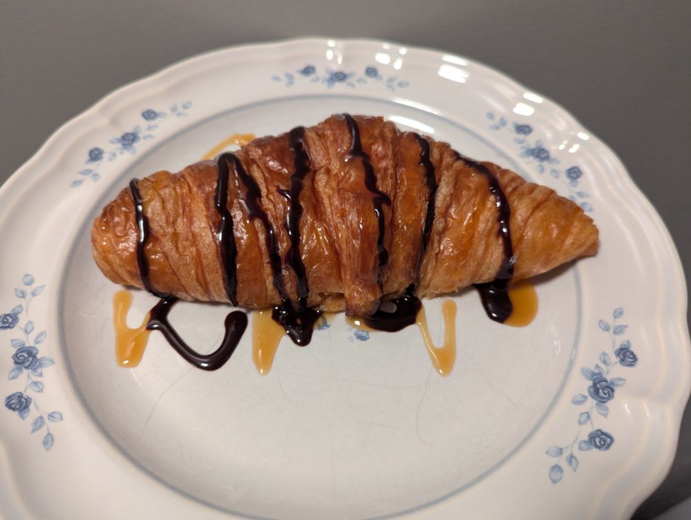 A Costco croissant covered in chocolate and caramel sauce