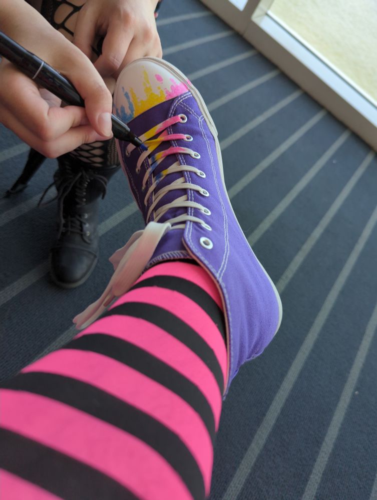 A purple canvas shoe being drawn on with pink, yellow, and blue