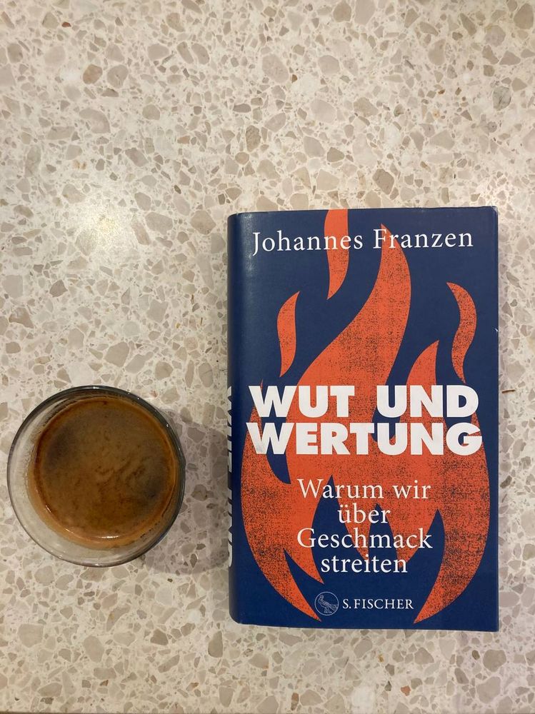 Das Bild zeigt eine Leseszene: Ein köstlichen Americano-Kaffee steht neben dem Buch "Wut und Wertungen. Warum wür über Geschmack streiten" von Johannes Franzen.