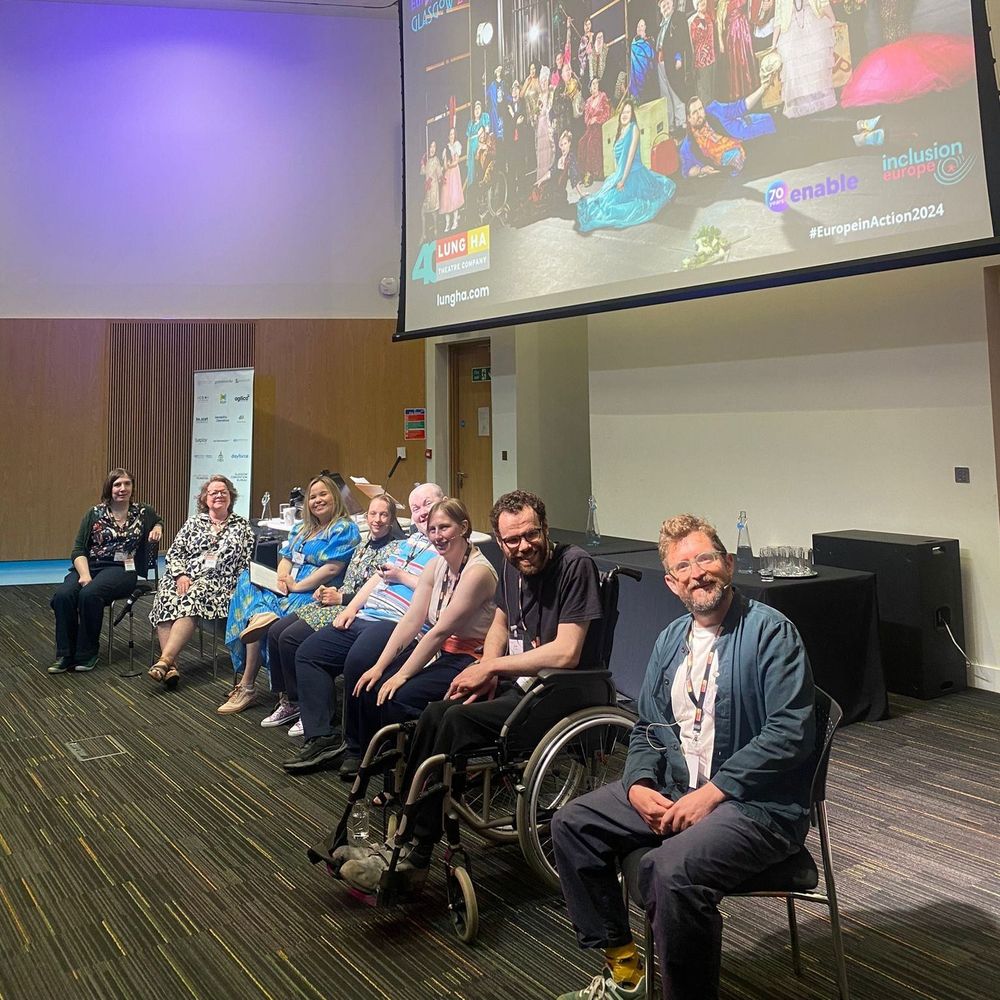 Members of the Castle Lennox cast and creative team sit in a row of chairs as part of a panel discussion. Everyone is facing the camera and smiling.