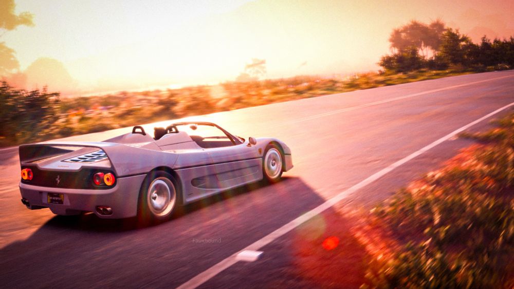 A silver Ferrari with the top off driving fast down a sunset road