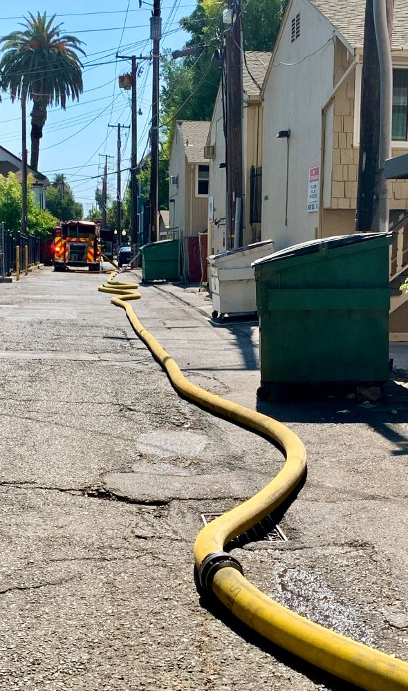 Fire hose snakes its way down an alley to a parked fire truck