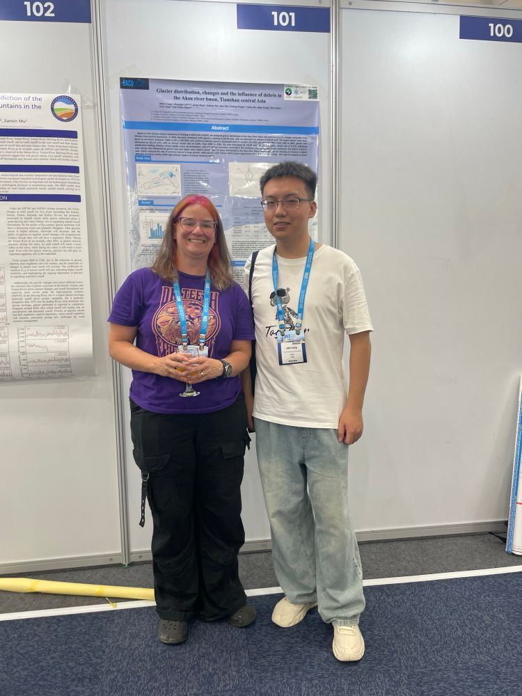 Two people standing next to each other in front of a conference poster