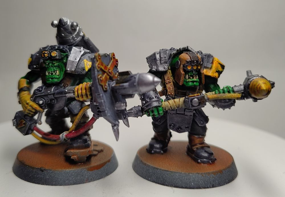 Two Space Ork miniatures, a pair of Wrecka Krew Orks, one holding a rocket launcher and the other welding a rocket on a stick