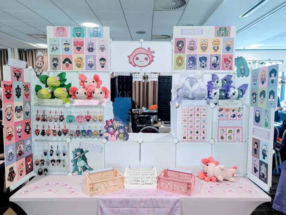 A photograph of my convention table, featuring a selection of my prints, plushies, pins and keychains.