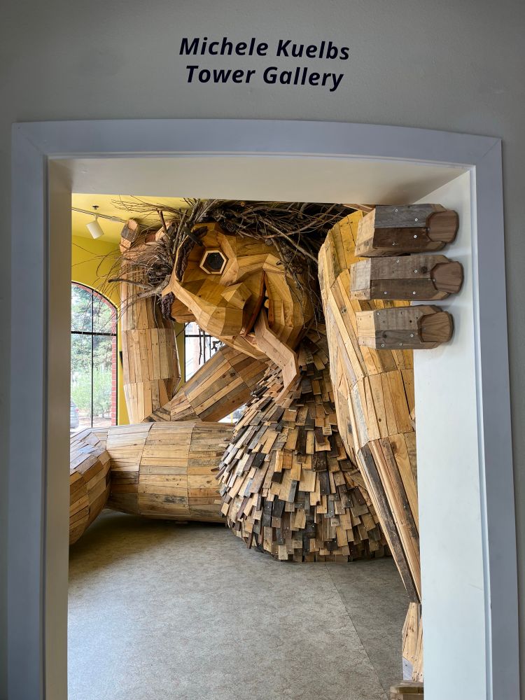 A giant wooden hand reaches through a doorway