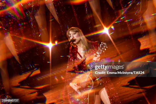 a photo of Taylor Swift from the Red set of the Eras tour in a sparkly red coat and bodysuit and playing guitar. Emma McIntyre, Getty Images