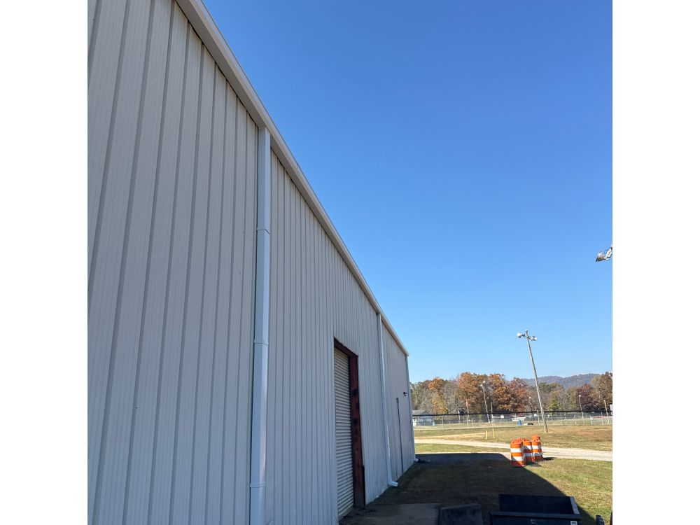 New Gutters and Downspouts installed on a metal building by WNC Roofing. 