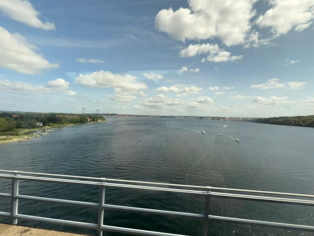 Utsikt ut av togvindu over en bru mot en vik.