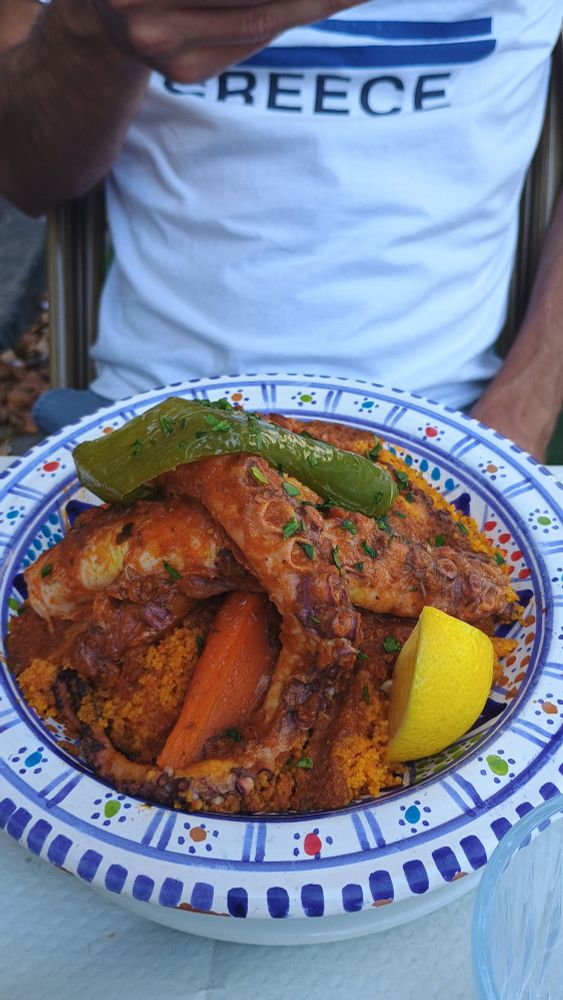Photo d'un couscous au poulpe dans une belle assiette bleu et blanche.