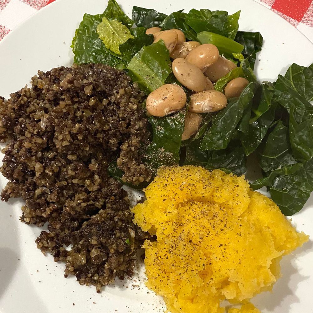 Plate with haggis (left), cabbage and white beans (top), mashed swede (bottom right) and a sprinkling of black pepper.