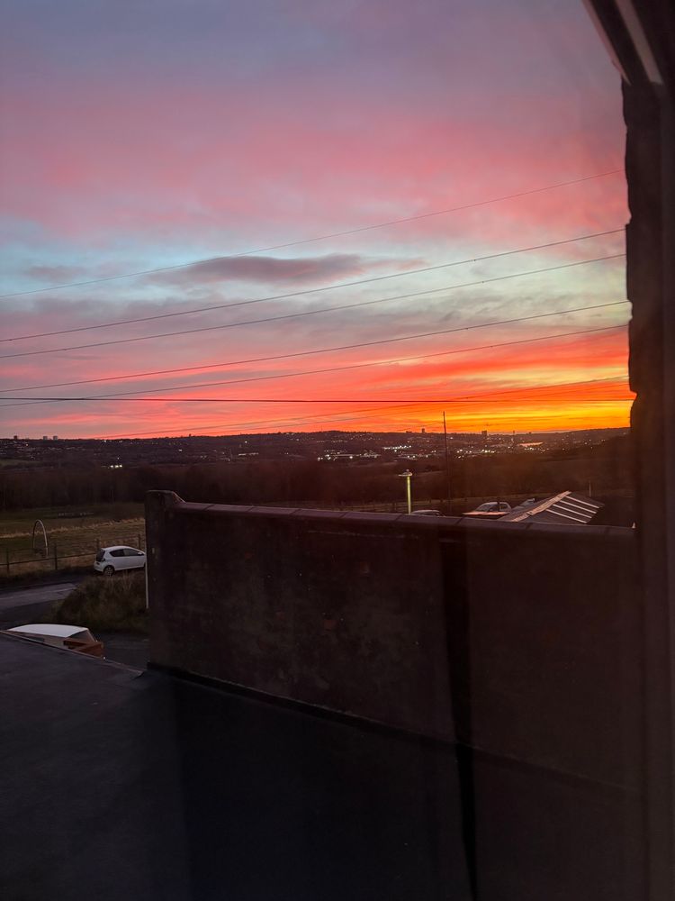 A beautiful sunrise in the North East of England, with deep oranges and yellows, and gentle pinks in the clouds with some light blue sky peeking through. 