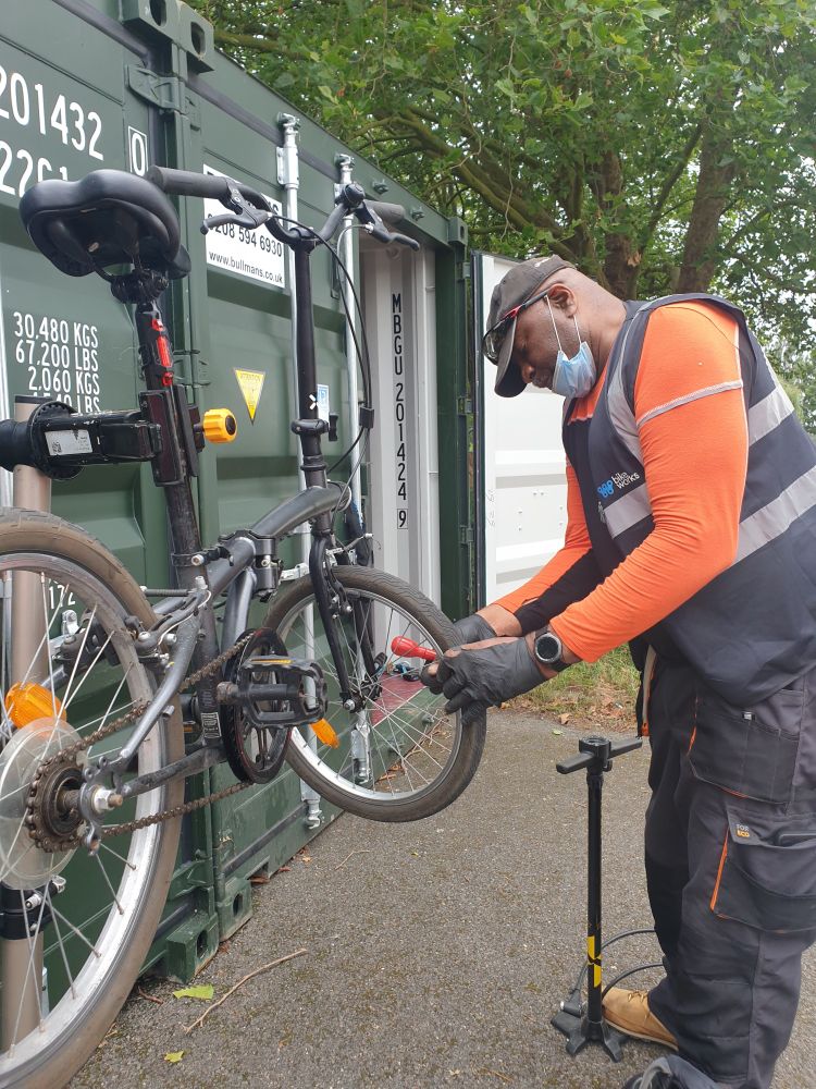Photograph of man working on a bike front wheel