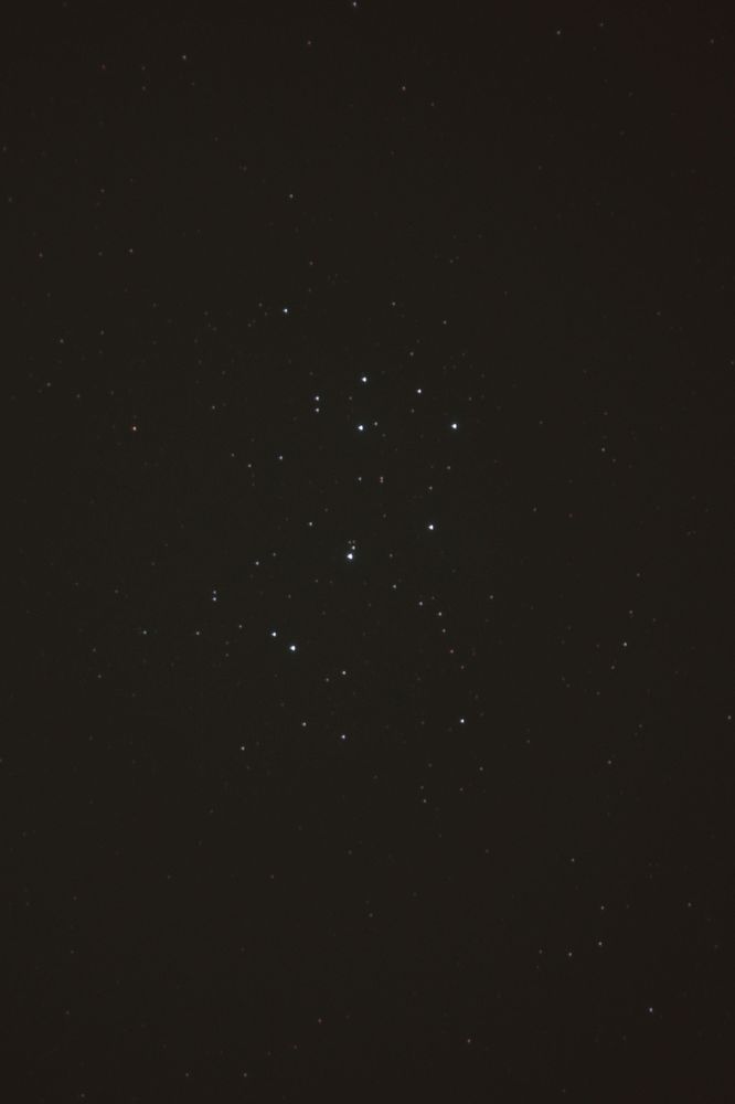 A dim photo of the seven sister constellation, the Pleiades.  The background is fairly dim, with the stars just poking out from the background